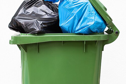 A wheelie bin overflowing with rubbish.